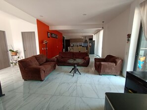 A modern living room with two brown sofas, a glass coffee table, and a TV stand.
