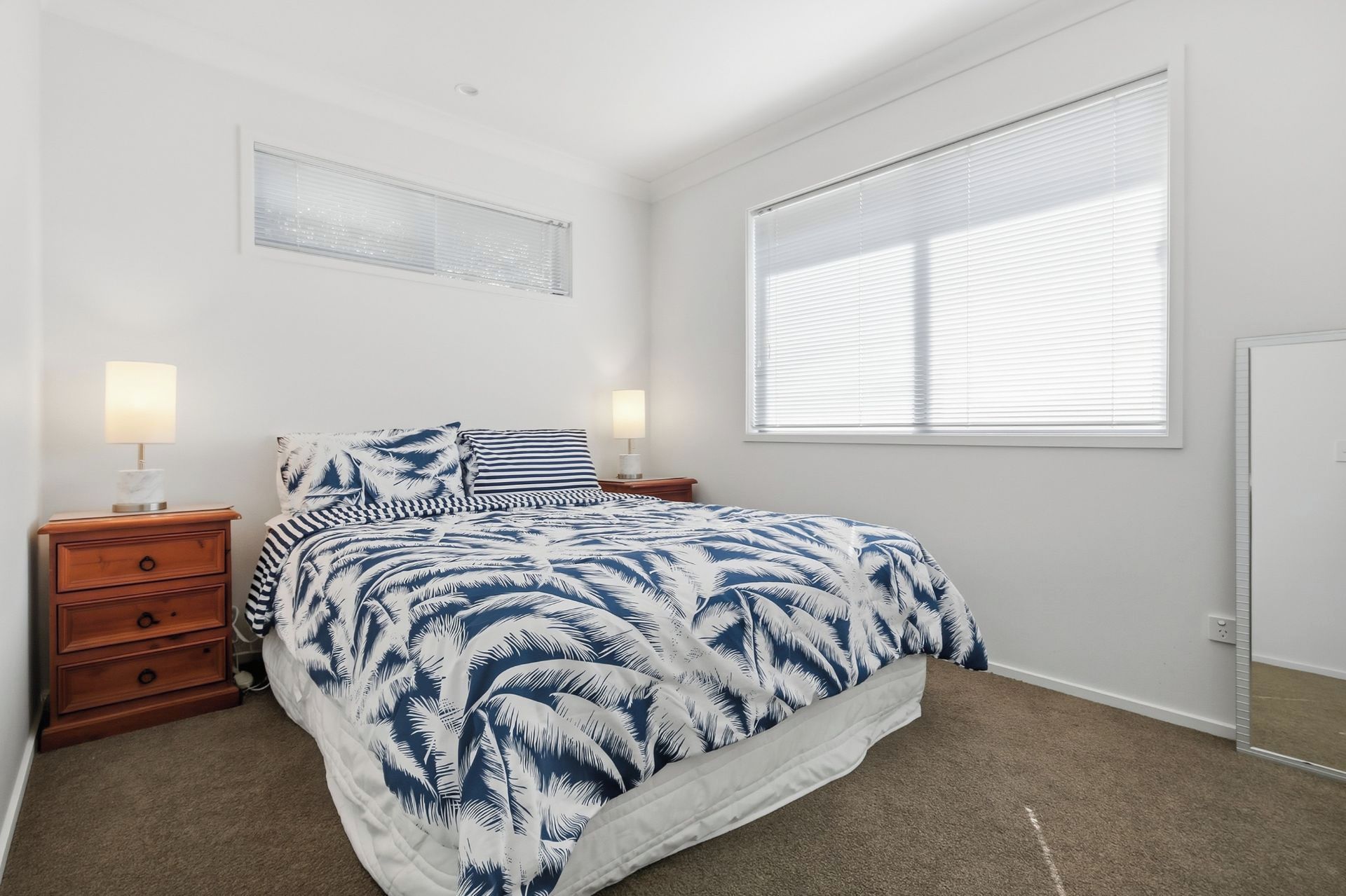 A bedroom with a bed, nightstands, lamps, a window, and a door.