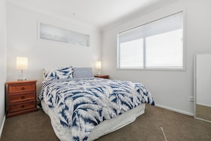 A bedroom with a bed, nightstands, lamps, a window, and a door.