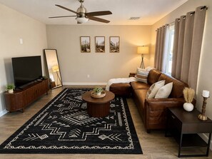 A living room with a sofa, a coffee table, a TV, and a ceiling fan.