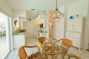 A spacious kitchen with white cabinets, a dining area with wicker chairs, and a hanging light fixture. - Waterfront heated pool home near beaches. 2 bedroom suites! (Port Charlotte)