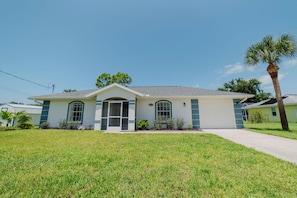 A single-story house with a front porch, a garage, and a well-maintained lawn. - Waterfront heated pool home near beaches. 2 bedroom suites! (Port Charlotte)