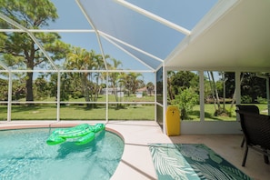 A pool area with a clear view of the surrounding landscape, including trees and a distant house. - Waterfront heated pool home near beaches. 2 bedroom suites! (Port Charlotte)