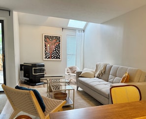 A living room with a sofa, a television, a glass coffee table, and a decorative painting.