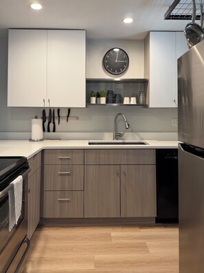 A modern kitchen with a stainless steel refrigerator, a sink, and wooden cabinets.