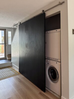 A room with a sliding door leading to a laundry area with a washing machine.