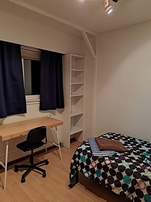 Un dormitorio con cama, escritorio, silla y armario.