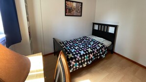A small, single-bed room with a wooden headboard, a framed picture on the wall, and a window with curtains. - Room-pretty Room -shared Accommodation (Coquitlam)