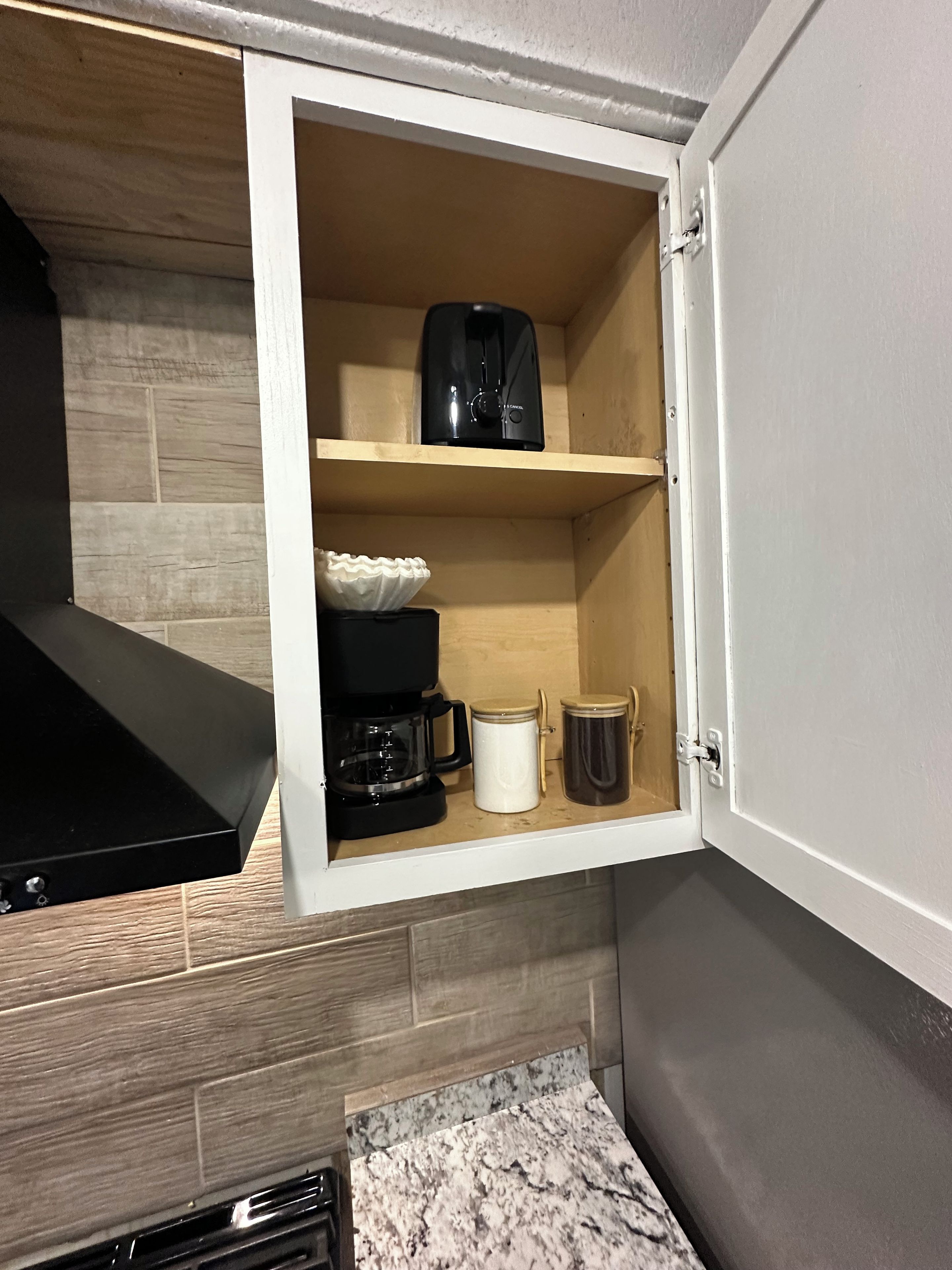 Une cuisine équipée d’une machine à café intégrée, d’une bouilloire et d’une tasse posée sur le plan de travail.