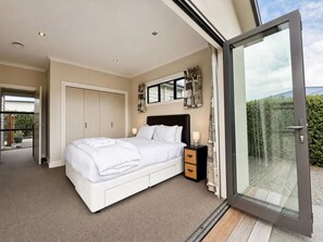 Ein Schlafzimmer mit einem Bett, Nachttischen und einer Schiebetür zu einem Balkon.