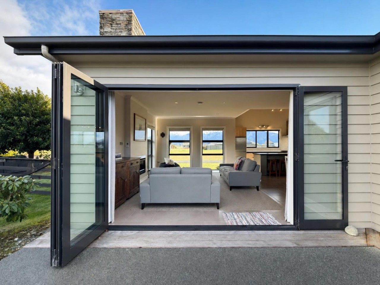 Un interior modern d'una casa amb una porta corredissa de vidre que dona a una zona d'estar, una cuina i un espai de menjador.