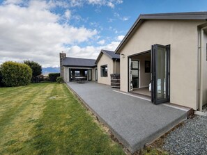 Ein modernes Haus mit überdachter Terrasse, Garage und gepflegtem Rasen.