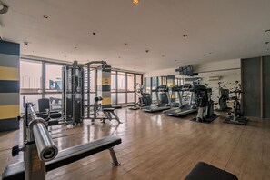 A gym with various exercise equipment, large windows, and a wooden floor. - Tropical Retreat • 24F Balcony • Sauna • Gym • Greenbelt • Makati (Makati)