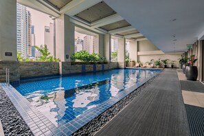 An indoor swimming pool with clear blue water, surrounded by stone walls and potted plants. - Tropical Retreat • 24F Balcony • Sauna • Gym • Greenbelt • Makati (Makati)