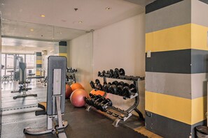Ein Fitnessstudio mit Trainingsgeräten, darunter ein Squat-Rack, Kurzhanteln und Medizinbälle.