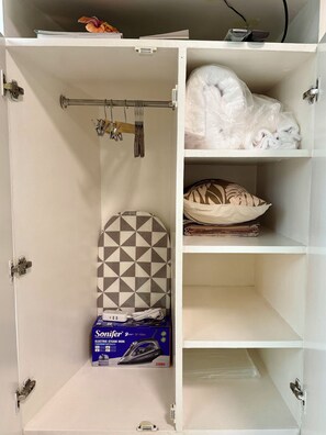 A storage closet with shelves, a hanging rack, and a box of an electric steam iron. - Tropical Retreat • 24F Balcony • Sauna • Gym • Greenbelt • Makati (Makati)