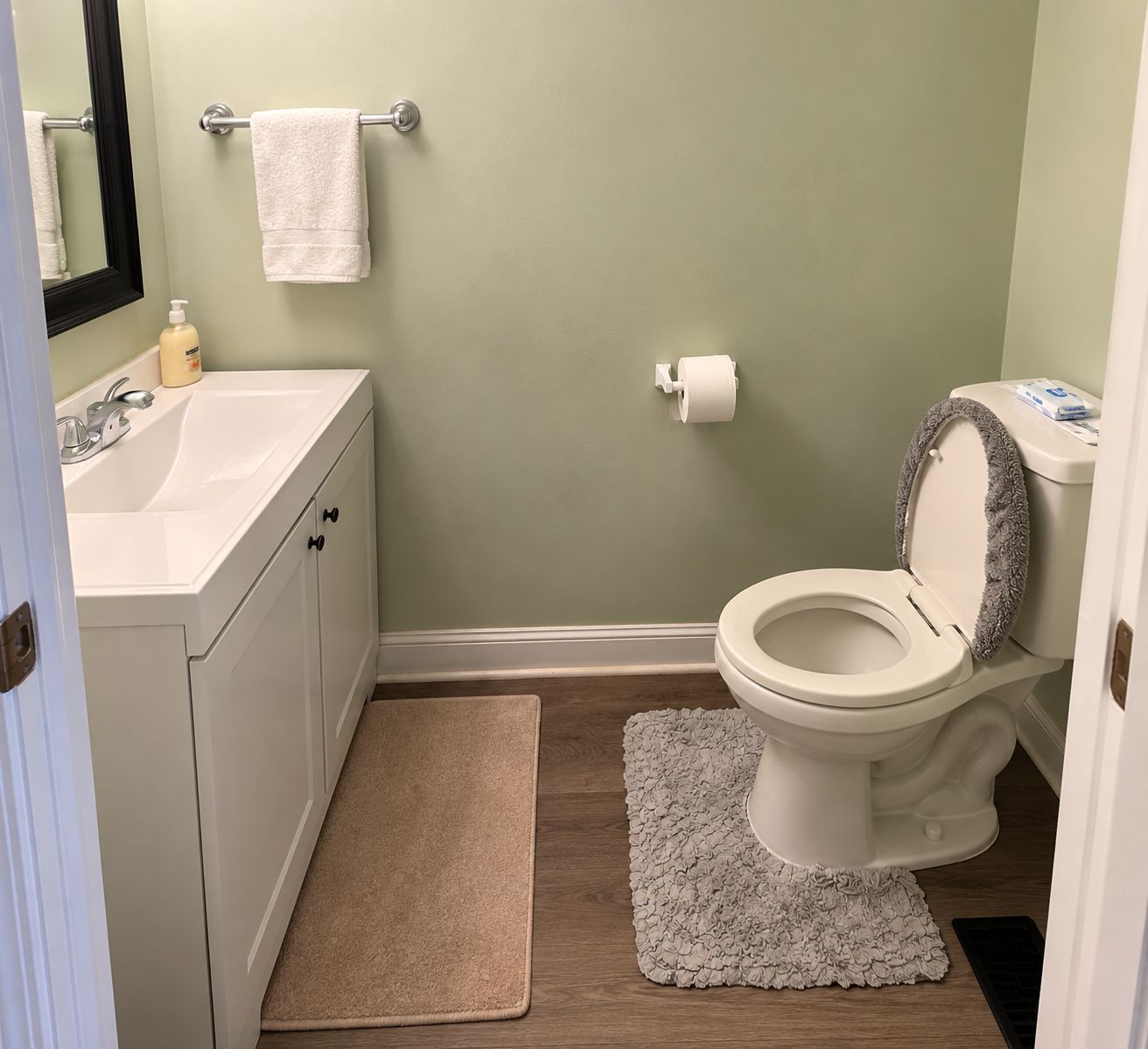 Un baño con lavamanos blanco, inodoro y una alfombra color beige.