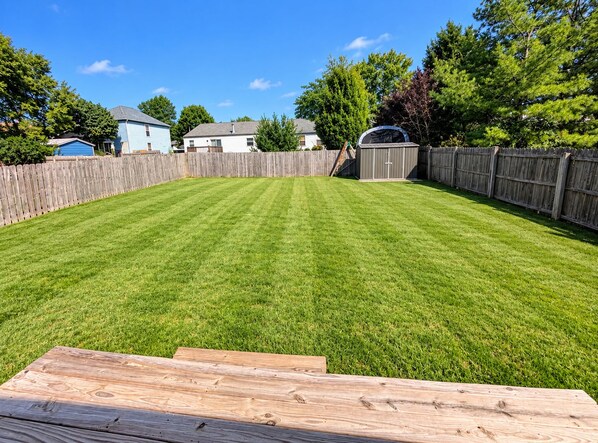 A well-maintained backyard with a wooden deck, a shed, and a wooden fence. - Furnished 3BR Home Near Columbus / Families, Business & Extended Stays (Pickerington)