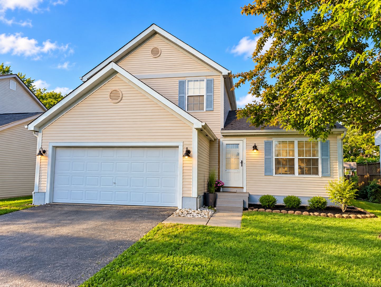 A two-story house with a garage, a front porch with a potted plant, and a well-maintained lawn.