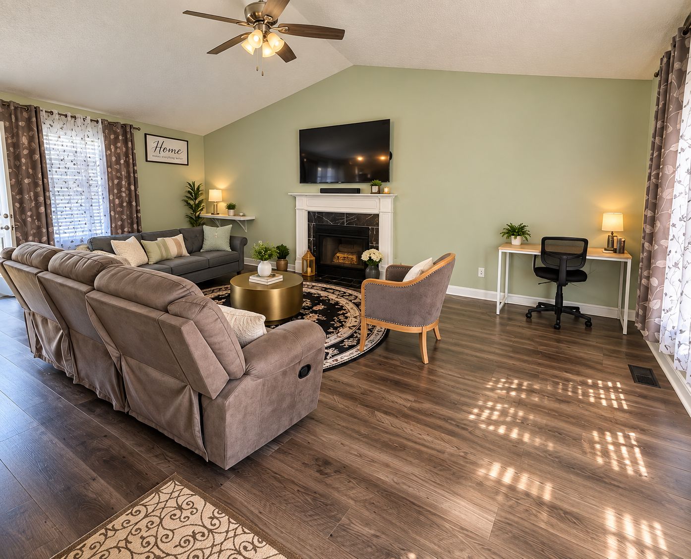 A living room with a sofa, armchair, coffee table, fireplace, and a TV mounted on the wall.