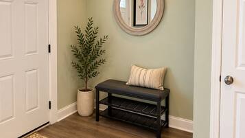 Un couloir avec un banc, une plante en pot et un tableau encadré accroché au mur.