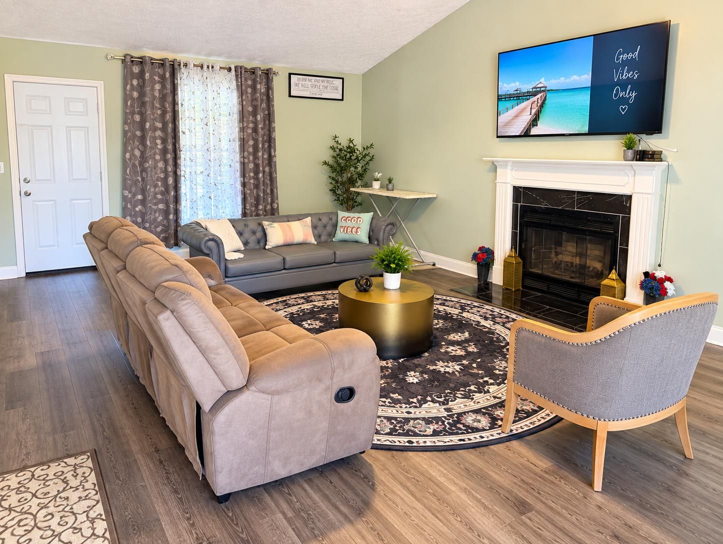 A living room with a sectional sofa, a round coffee table, a fireplace, and a television mounted on the wall.