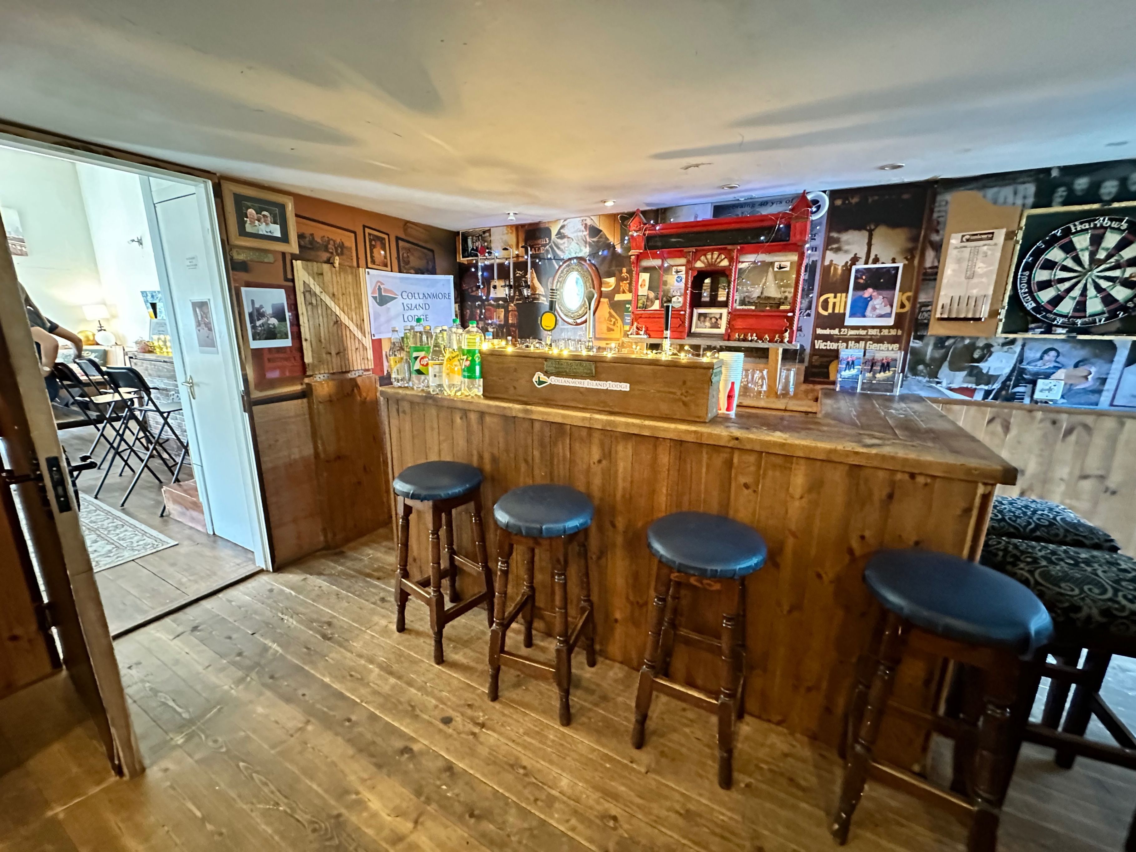 A bar area with stools, a dartboard, and a counter with various items.