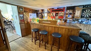 A bar area with stools, a dartboard, and a counter with various items.