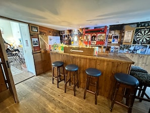 A bar area with stools, a dartboard, and a counter with various items.