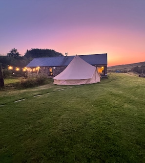 A grassy field with a tent and a building with a sloped roof.