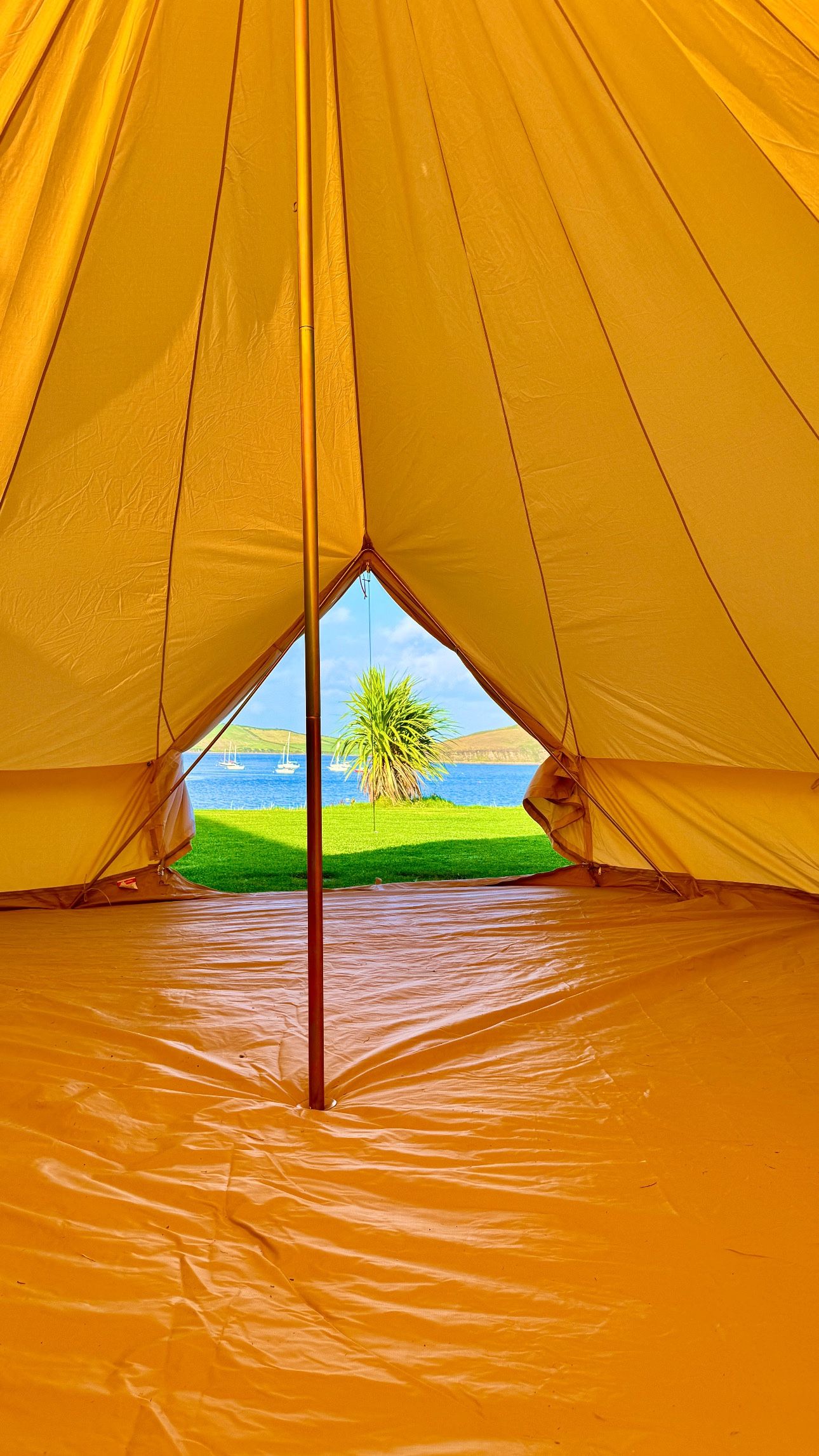 A tent with a view of a body of water and greenery.