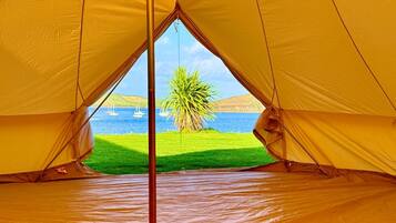A tent with a view of a body of water and greenery.