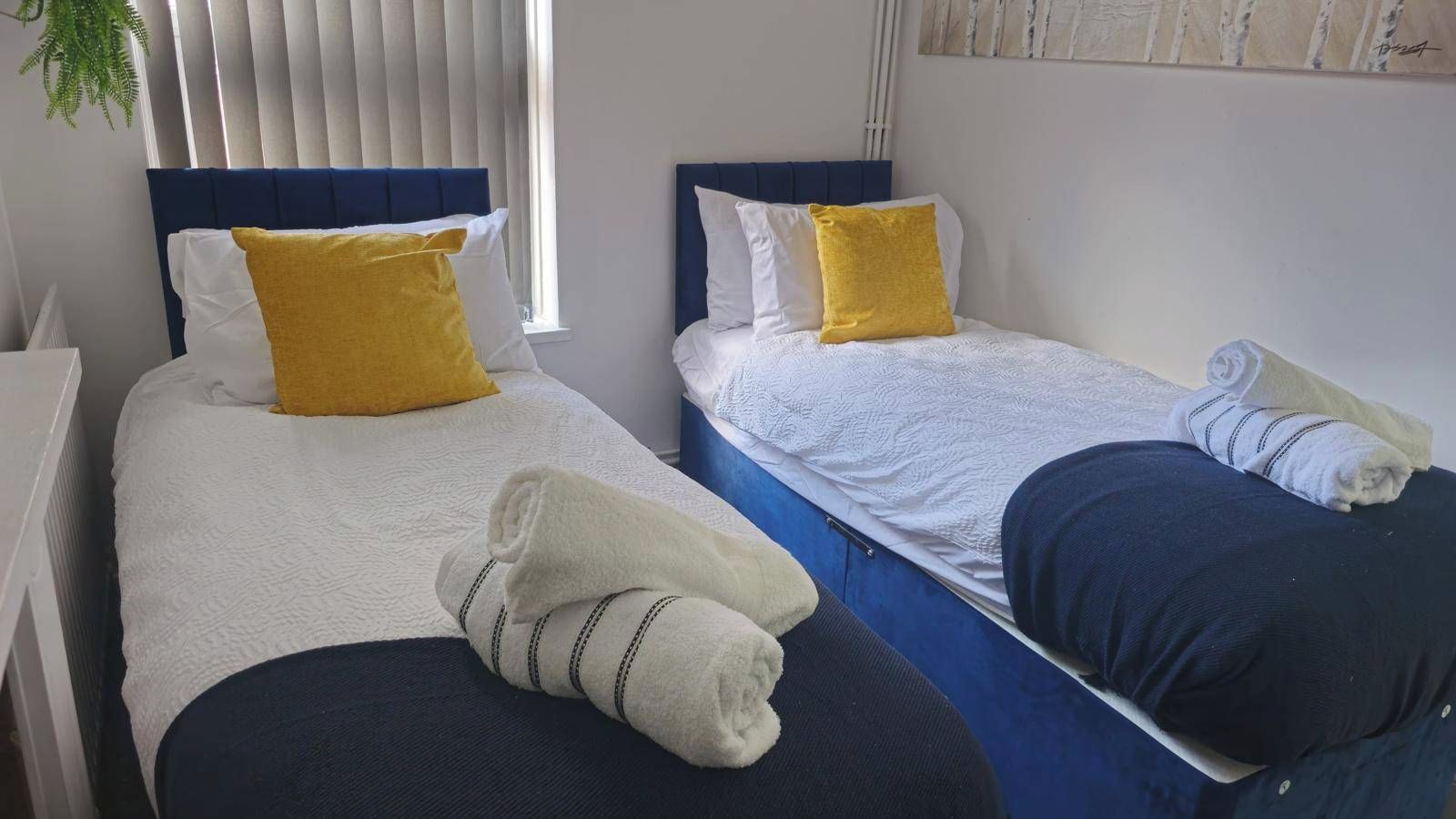 Two single beds with headboards, white bedding, and yellow pillows.