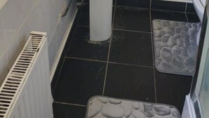 A bathroom with a white sink, black and white tiled walls, a white toilet, and a black floor. - Sensational- Haven place (Leicester)