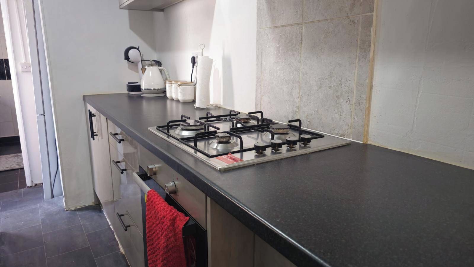 A kitchen with a gas stove, cabinets, and a red towel hanging on the door.