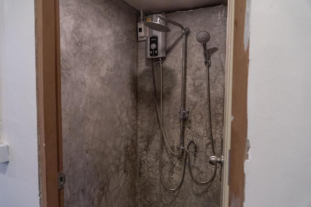 Une douche équipée d’un pommeau de douche à main et d’un pommeau de douche fixé au mur, reliés par un tuyau flexible.