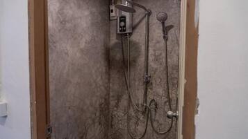 Une douche équipée d’un pommeau de douche à main et d’un pommeau de douche fixé au mur, reliés par un tuyau flexible.