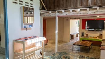 A room with a wooden bench, a television mounted on the wall, and a patterned floor.