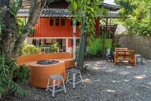 Un edificio tradicional japonés con fachada roja, un banco de madera y un pequeño espacio al aire libre con taburetes.