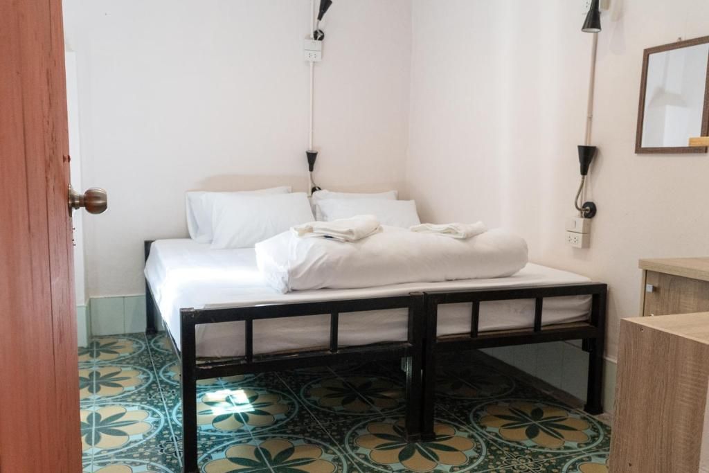 Une chambre à coucher avec un lit, une tête de lit en bois, une table de chevet, un miroir et des carreaux de sol à motifs.