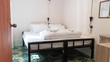 Une chambre à coucher avec un lit, une tête de lit en bois, une table de chevet, un miroir et des carreaux de sol à motifs.
