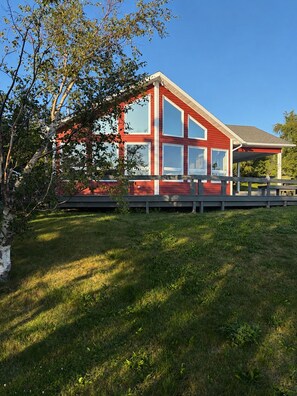 A red building with large windows and a covered porch area. - Mae’s place l Horse Chops Pond Retreat (Cape Broyle)