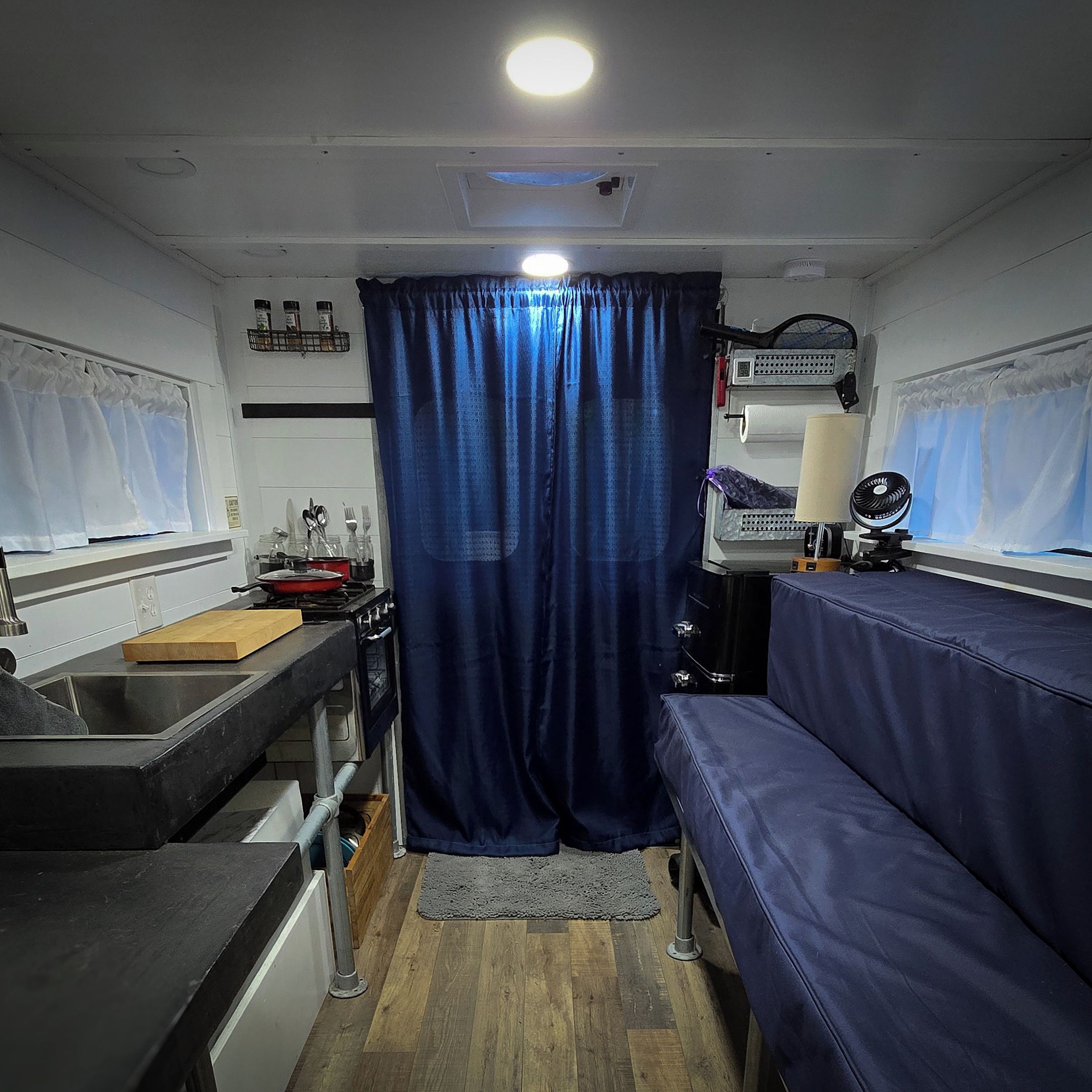 Una cucina compatta con lavello, fornello e una tenda blu.
