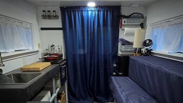 Una cucina compatta con lavello, fornello e una tenda blu.