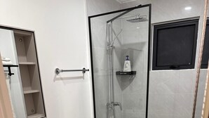 A modern bathroom with a glass-enclosed shower, a toilet, a sink, and a mirror. - Cozy 2-bedroom bungalow with AC in charming Runaway Bay. Hosts up to 4  persons. (Runaway Bay)