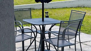 A patio with a table and chairs, an umbrella, and a view of a landscape with buildings and a body of water. - Cozy 2-bedroom bungalow with AC in charming Runaway Bay. Hosts up to 4  persons. (Runaway Bay)