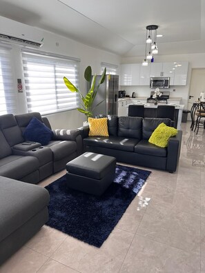 Una sala de estar moderna con un sofá modular, una mesa de centro y una planta grande en maceta.