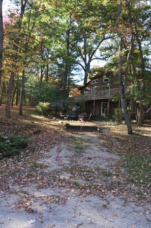 A two-story building with a balcony, surrounded by trees and a gravel path. - Cedar House on Highland Trail + Sleeps 14 +  Spacious Cottage Retreat (Stanwood)