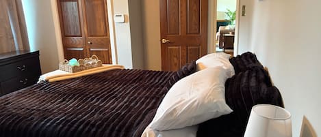 A bedroom with a bed, a bedside lamp, a dresser, and a door.