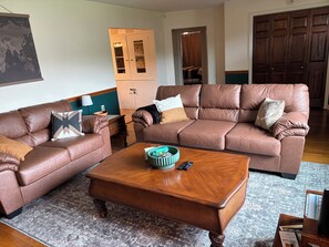 Ein Wohnzimmer mit zwei braunen Ledersofas, einem Holztisch, einem gemusterten Teppich und einer Karte an der Wand.